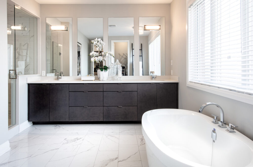 Ensuite with double sink dark vanity, stand alone tub and walk in shower.