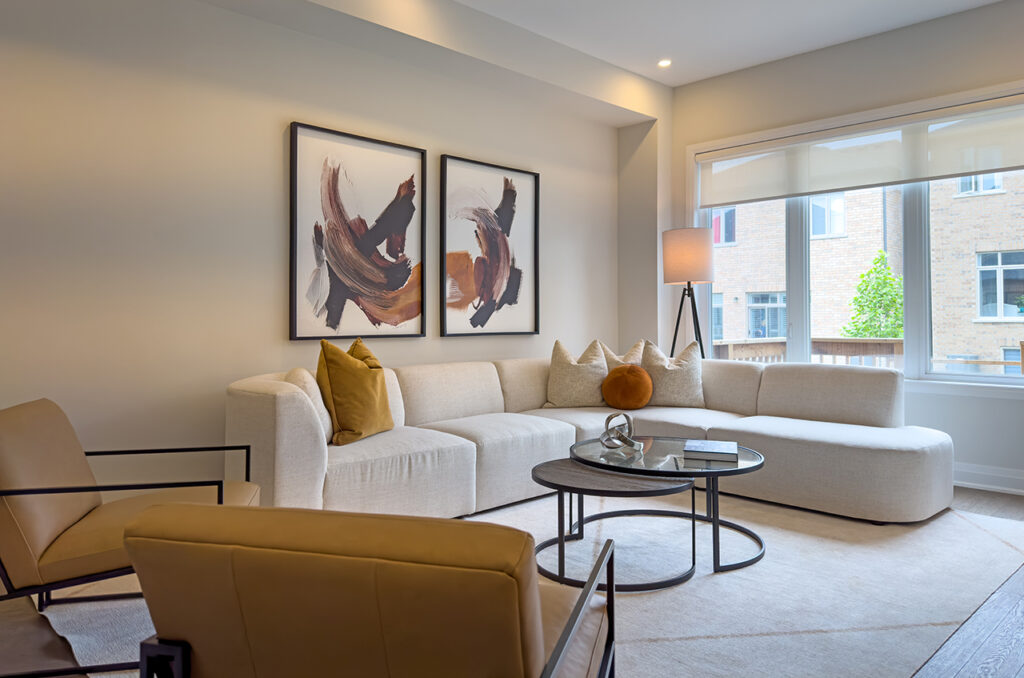 Contemporary living room with cream sectional, round glass coffee table, and warm accents.