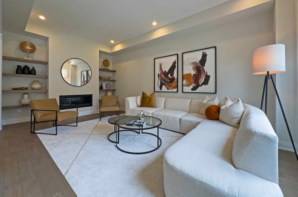 Contemporary living room with cream sectional, round glass coffee table, fireplace, with shelves and chairs.