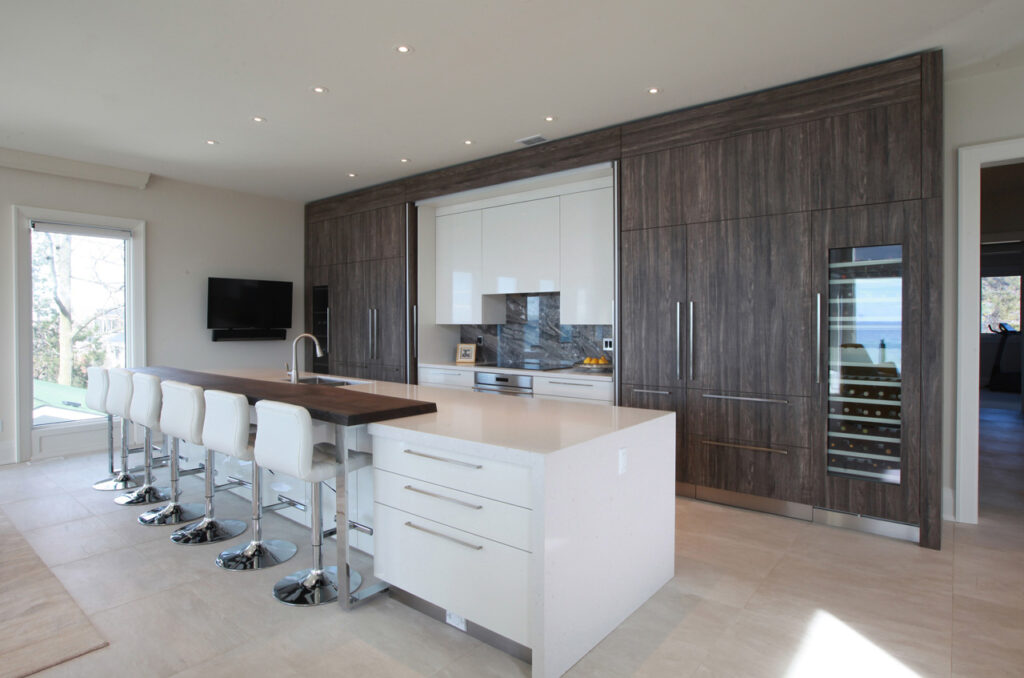 Open concept kitchen with white and wood island, and hidden appliances showing behind dark wood cabinets.