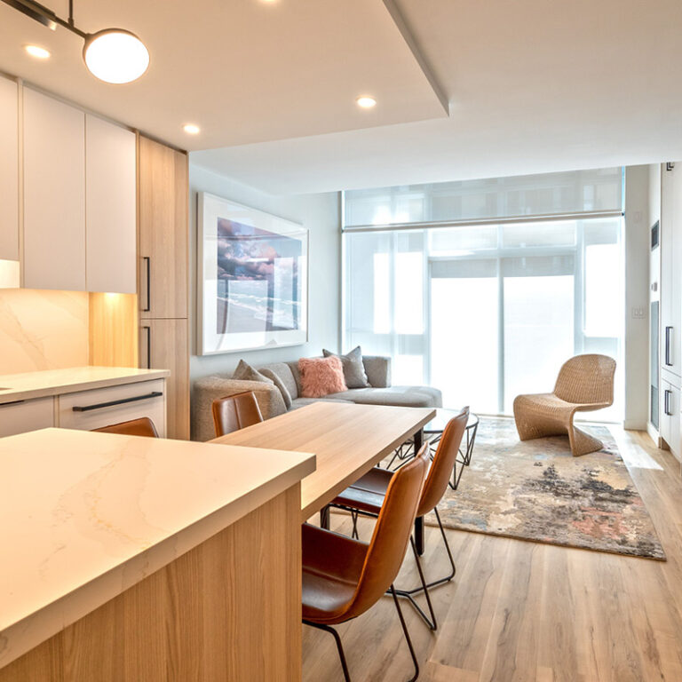 Renovated condo view of kitchen island with attached table open to living room.